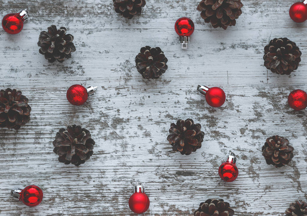 Weihnachtsmuster. Hintergrund mit Tannenzapfen und roten Neujahrskugeln. Flache Lage, Draufsicht.  - Foto, Bild