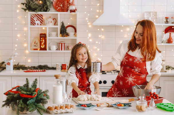 Mom and daughter in the New Year's kitchen together prepare dough for Christmas cookies. - Foto, imagen