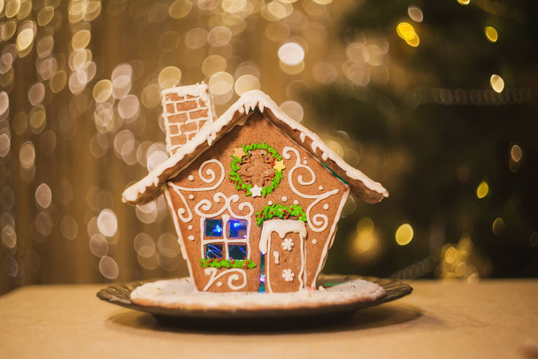 Magique maison en pain d'épice maison avec des lumières dorées et bokeh en arrière-plan. Joyeux Noël et bonne année Salutations, carte postale, fond - Photo, image