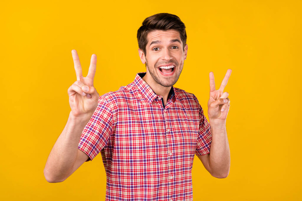 Photo of cheerful amazed happy young man show v-signs good mood hello isolated on yellow color background. - Foto, immagini