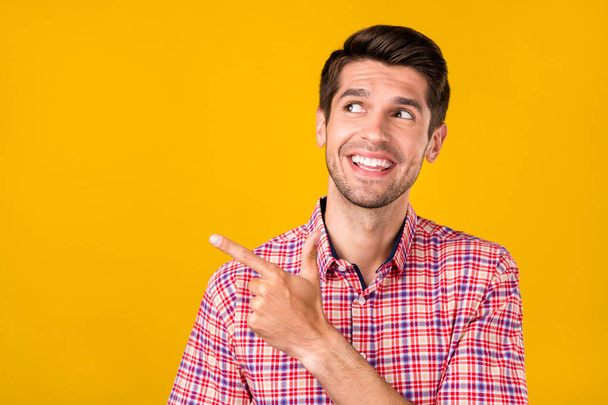 Portrait of attractive cheerful guy demonstrating copy blank place space ad like follow isolated over bright yellow color background. - Foto, Imagem