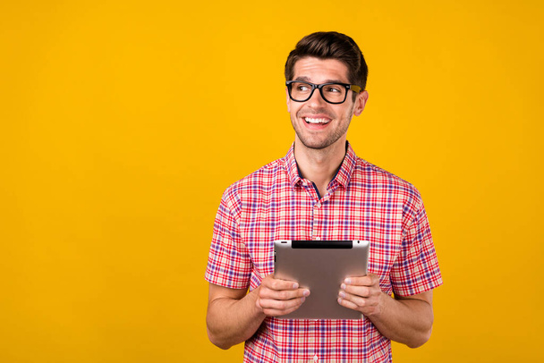 Portrait of attractive cheerful guy using ebook app 5g deciding copy space place advert isolated over bright yellow color background - Photo, Image