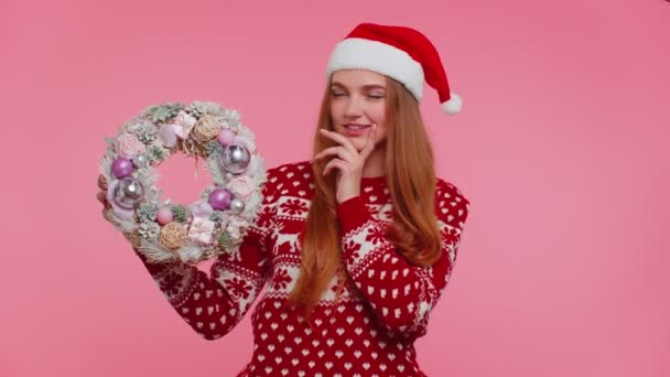 Volwassen glimlachend meisje in rode kerstvakantie trui hold verhogen punt vinger op feestelijke krans speelgoed - Video