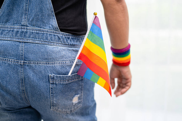 ゲイ、レズビアン、バイセクシャル、トランスジェンダー、人権の6月の社会でLGBTプライド月間のシンボルである虹の旗のリストバンドを身に着けているアジアの女性は毎年祝う. - 写真・画像