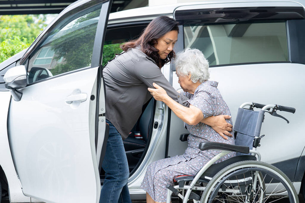 Ayuda y apoyo asiático senior o anciano anciana mujer paciente sentado en silla de ruedas prepararse llegar a su coche, saludable fuerte concepto médico. - Foto, imagen