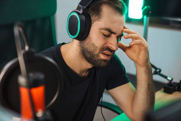 Angry devastated young man gamer wearing headphones lost a game on computer - Zdjęcie, obraz