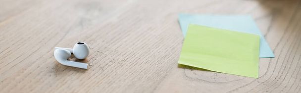Earphones near sticky notes on table in office, banner  - Photo, image