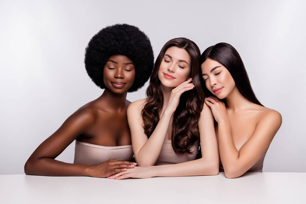 Фото трех молодых привлекательных женщин мечта насладиться чувственным совершенством телесного ухода изолированы на сером фоне цвета - Фото, изображение