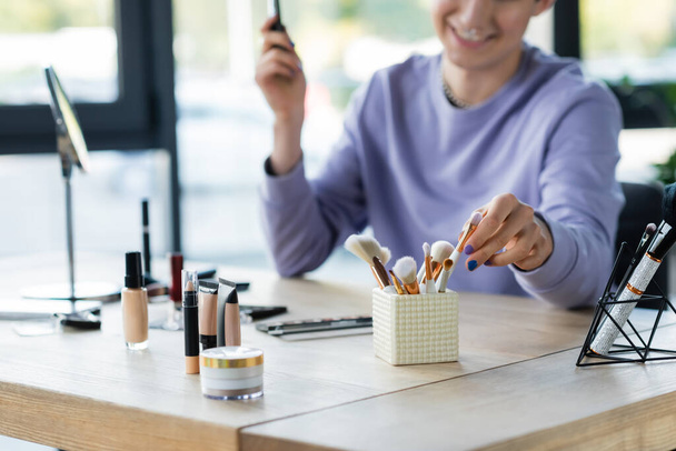 Cropped view of decorative cosmetics near blurred transgender person in studio  - Photo, Image