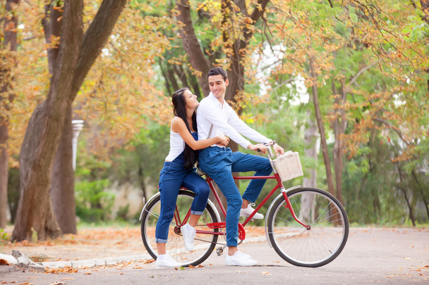 Teen couple with bike in the park in autumn time - 写真・画像