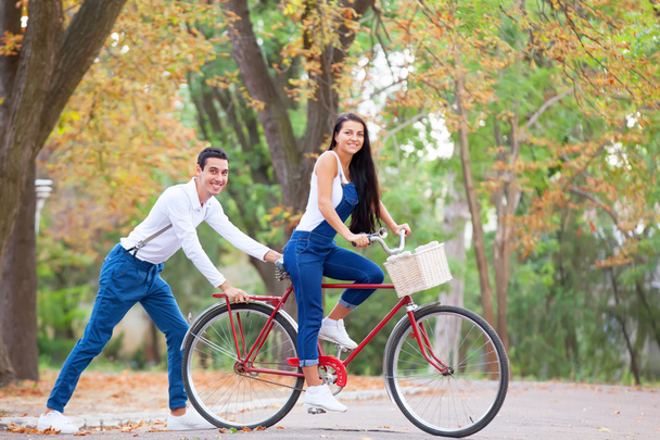 Teen couple with bike in the park in autumn time - Photo, Image