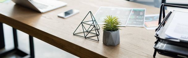 Plant near paper tray and blurred devices in office, banner  - Фото, изображение