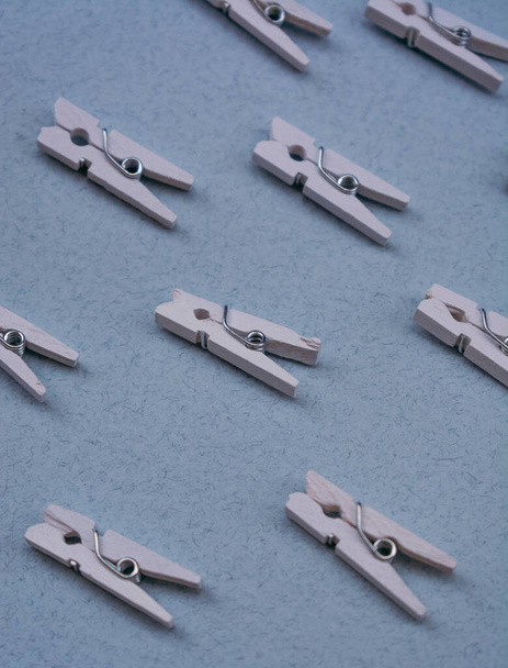 Small white wooden clothespins. Blue background. Minimalistic pattern. Clothespins for office work - Photo, image