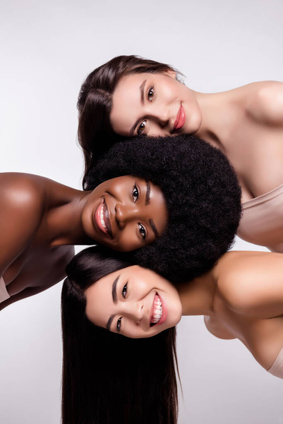Φωτογραφία από τρία νεαρά ελκυστικά κορίτσια χαρούμενο θετικό χαμόγελο φροντίδα των μαλλιών καθαρό απομονωμένο πάνω από γκρι φόντο χρώμα - Φωτογραφία, εικόνα