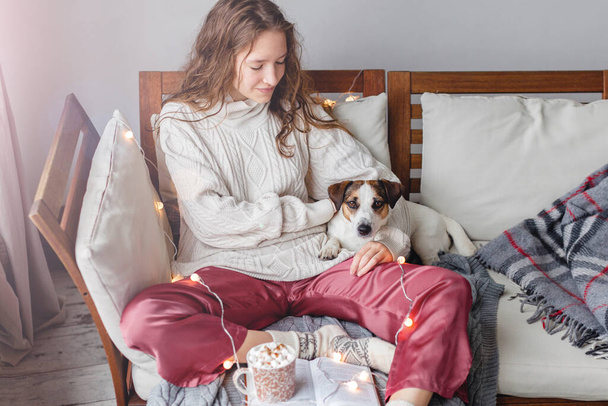 Young woman with dog drinking warm coffee at home - Fotoğraf, Görsel
