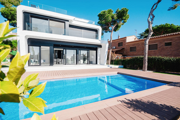 Casa branca moderna de luxo com grandes janelas com vista para um jardim paisagístico mediterrânico com palmeiras e piscina azul. Casa de alta tecnologia estilo.  - Foto, Imagem