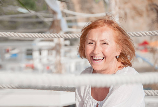 Close up portrait of a happy smiling mature woman Relaxing on the beach by the sea.  - Photo, Image