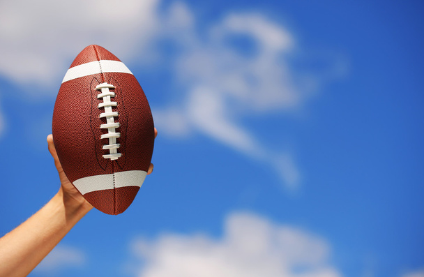 American Football in Hand over Blue Sky - Fotografie, Obrázek