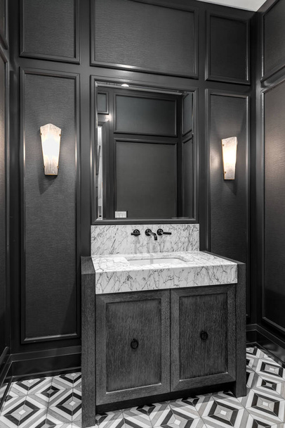 ELMHURST, IL, Estados Unidos - 2 DE OCTUBRE DE 2020: Un baño negro con paredes de cartón y listón, un armario de madera oscura, suelo de mosaico y una encimera de granito. - Foto, Imagen