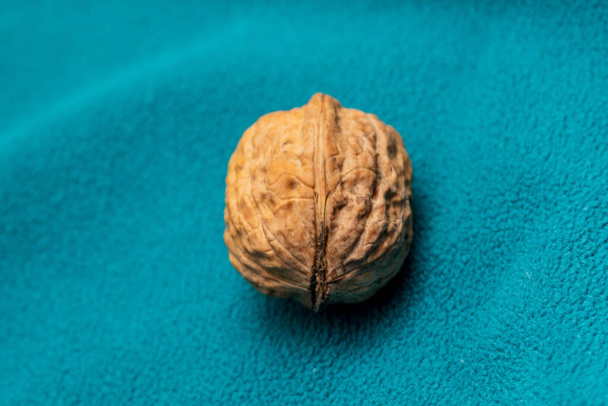 Close-up shot of a yellow walnut on a turquoise background - Foto, Bild