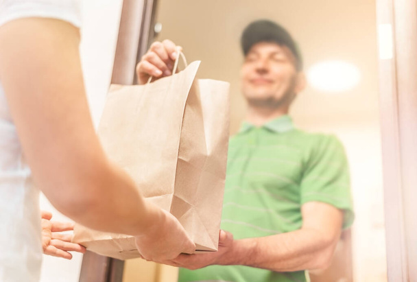 Woman hand accepting a delivery food package from professional deliveryman at home. - Photo, Image