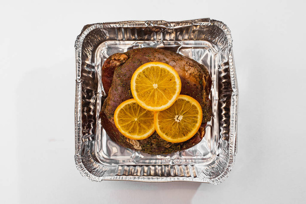 вид зверху смачне запечене домашнє м'ясо в коробці з фольги, прикрашене лимонними шматочками
 - Фото, зображення