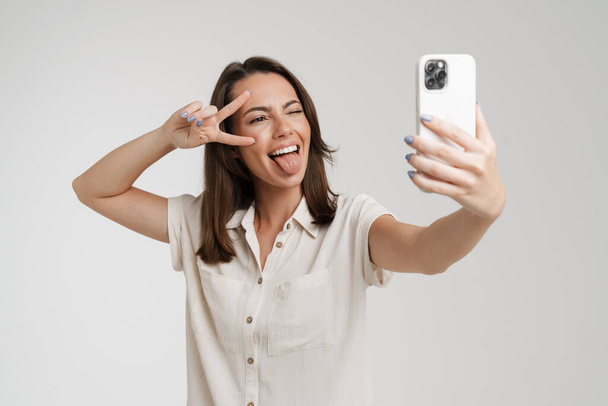 Young european woman taking selfie photo on mobile phone isolated over white background - Fotografie, Obrázek