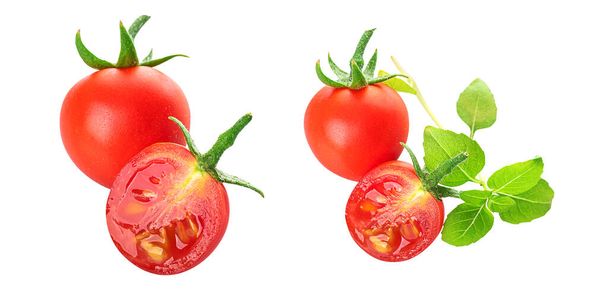 Jóvenes hermosos tomates rojos cereza enteros y mitades con hojas frescas de albahaca verde joven aisladas sobre un fondo blanco - Foto, Imagen
