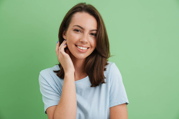 Young european woman smiling and looking at camera isolated over green background - Photo, image