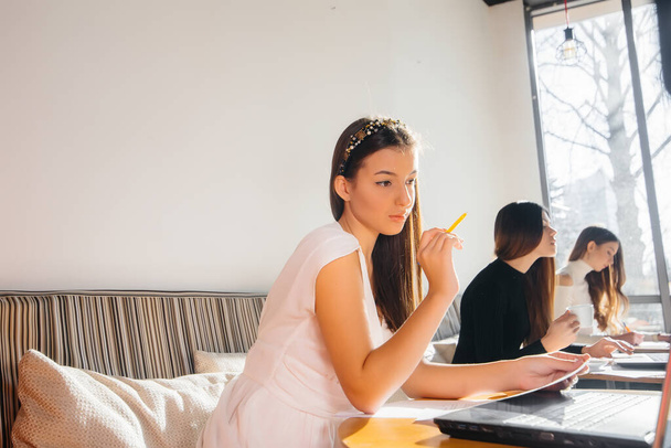 A group of young girls sit in an office and work at computers. Communication and training online. - 写真・画像