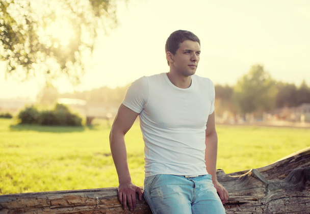 Handsome man outdoors, soft sunny sunset, man pensive looks away - Photo, Image