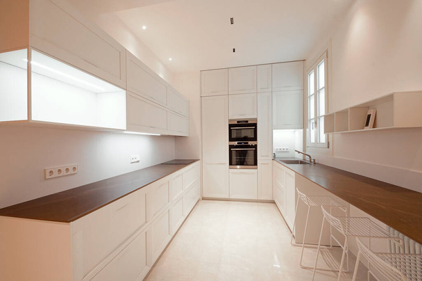 Klasická moderní kuchyň s dřevěnými a bílými detaily, minimalistickým designem interiéru, moderními systémy zvedání nábytku, otevřeným nábytkem a otevřeným mrazákem. Kuchyně s integrovanými spotřebiči. - Fotografie, Obrázek