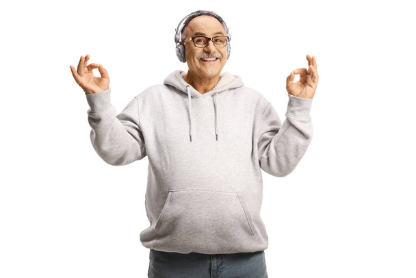 Happy mature man listening music on headphones and meditating isolated on white background - Фото, изображение