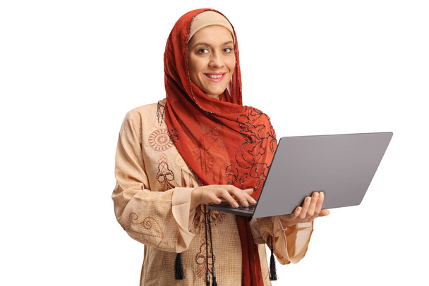 Young woman wearing a hijab and holding a laptop computer isolated on white background - Fotografie, Obrázek