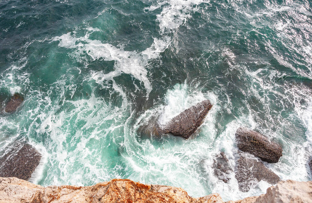 Top view photo of  Atlantic ocean waves hitting rocks on the beach with turquoise sea water. Amazing rock cliff seascape in the Portuguese coastline. Peniche costline.  - Photo, Image