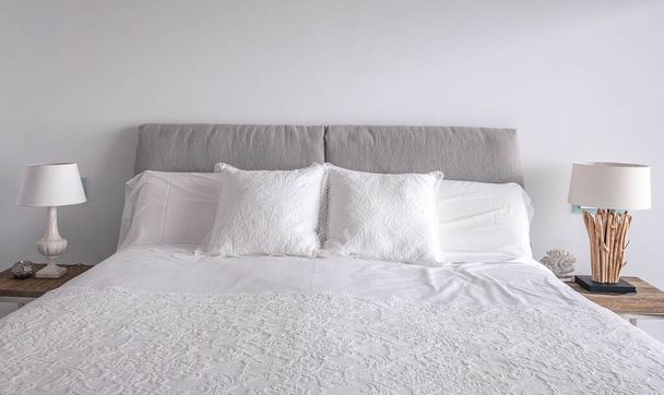 Ледачі білі подушки на спальному ліжку. Зручні м'які подушки та декоративні лампи
.  - Фото, зображення