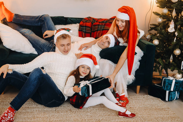Close-up portrait of a happy family sitting on a sofa near a Christmas tree celebrating a holiday. - Foto, imagen