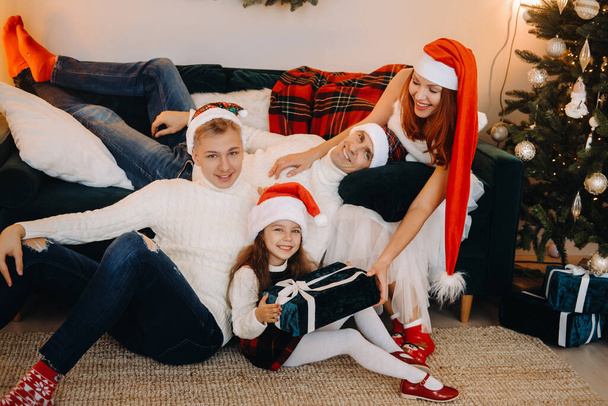 Close-up portrait of a happy family sitting on a sofa near a Christmas tree celebrating a holiday. - Fotó, kép