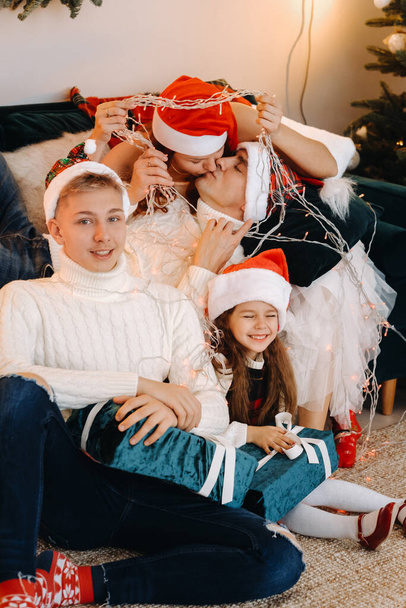 Close-up portrait of a happy family sitting on a sofa near a Christmas tree celebrating a holiday - Photo, image