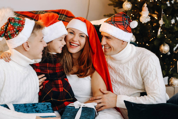 Close-up portrait of a happy family sitting on a sofa near a Christmas tree celebrating a holiday - Fotó, kép