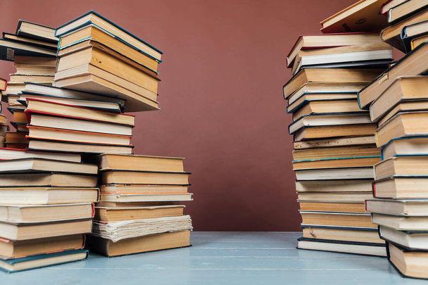 stacks of educational books in the library on a brown background - Photo, Image