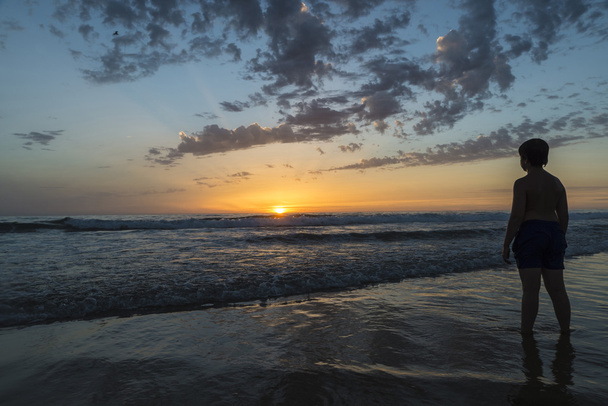 Мальчик купается на пляже в сумерках
 - Фото, изображение