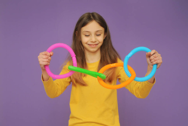kicsi okos lány sárga ruhában játszik trendi játék pop tube - Fotó, kép