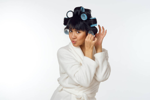 housewife in a white coat curlers on her head emotions housework - Foto, imagen