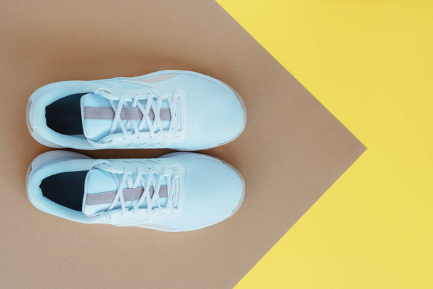 White sneakers on beige and yellow background. Sport and fitness concept. Top view, flat lay - Foto, afbeelding