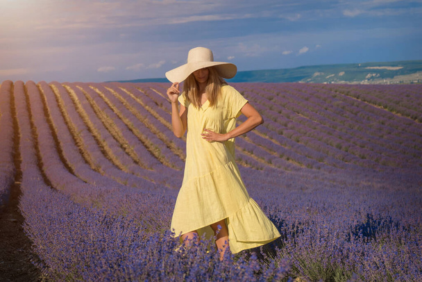 Tyttö keltaisessa mekossa laventelipellolla. - Valokuva, kuva