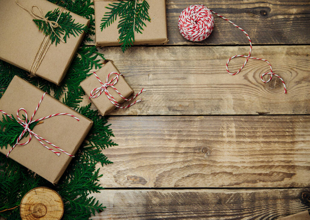 Boxes packed in kraft paper and green branches on a wooden background. Sale. Environmentally friendly material.Christmas and New Year. - Foto, imagen