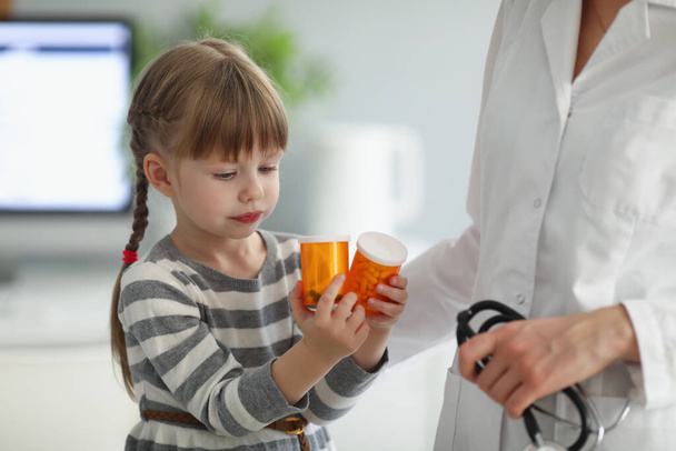 Child playing with bottles full of medication while on doctors appointment - Foto, Imagen