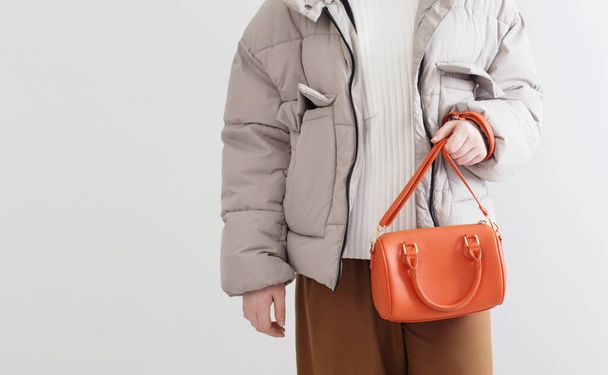 woman in  short down jacket with an orange handbag - Fotoğraf, Görsel