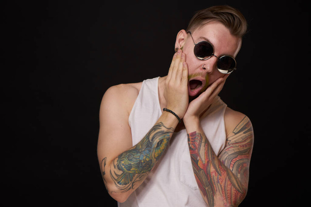 handsome man with tattoos on his arms fashion sunglasses dark background - Foto, Imagem